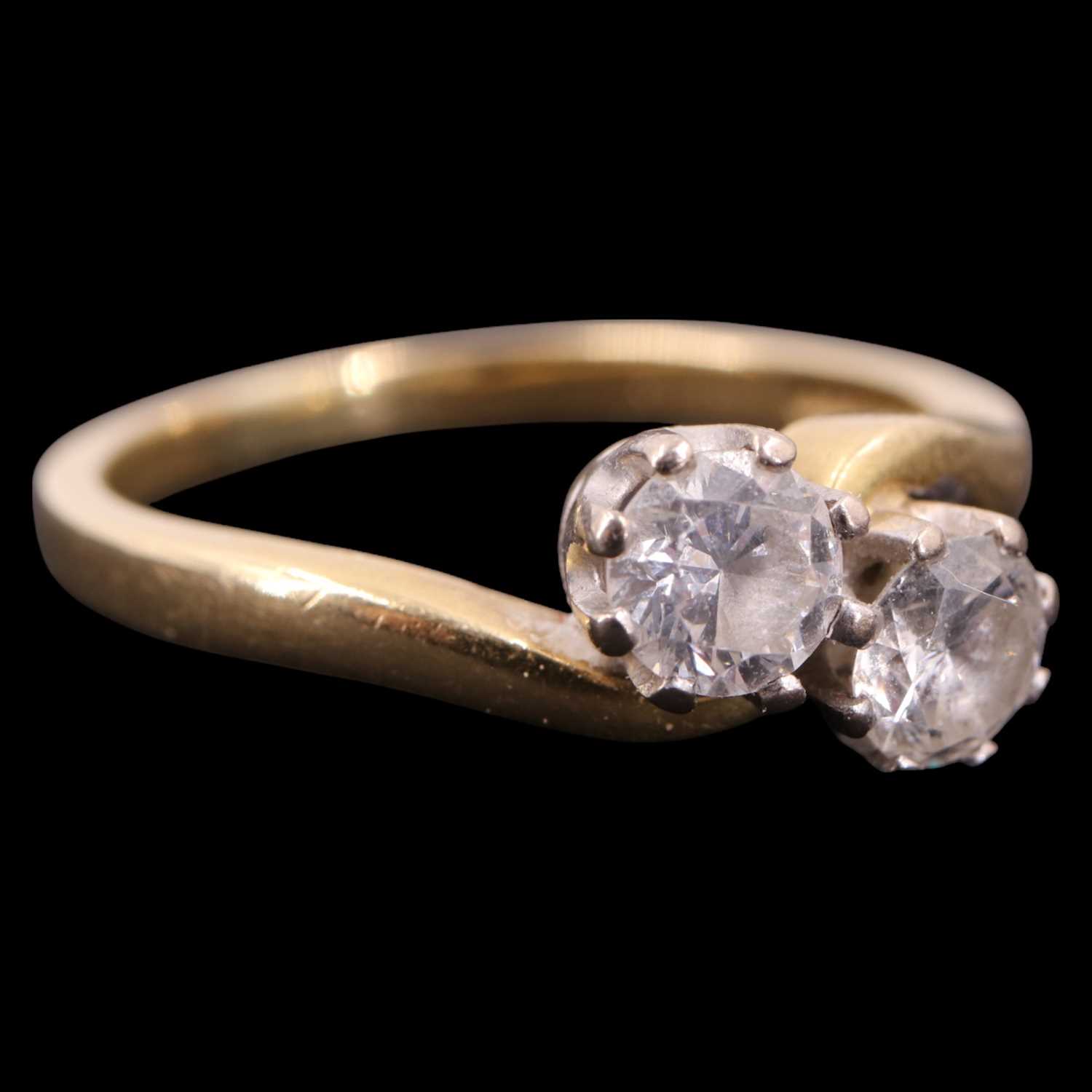 Lot 1394 - A two-stone diamond crossover ring, comprising...