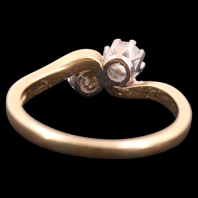 Lot 1394 - A two-stone diamond crossover ring, comprising...