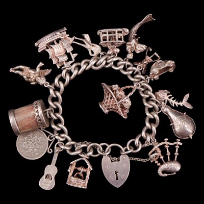 Lot 1039 - A vintage white metal charm bracelet, having a...