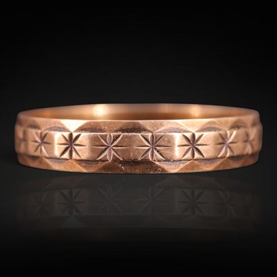 Lot 1267 - A 1970s 9 ct gold band, bearing a row of stars...